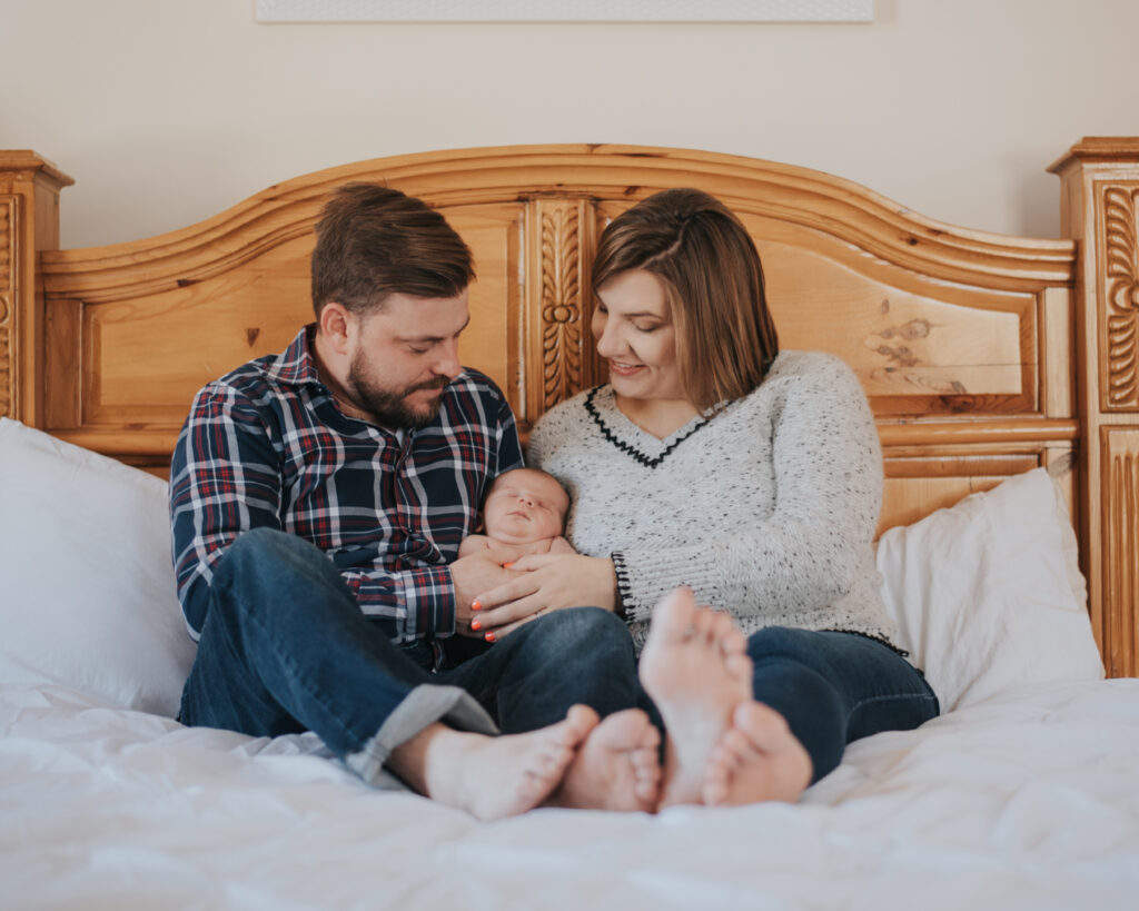 Newborn baby on bed with parents | Stephanie Acar Portraits